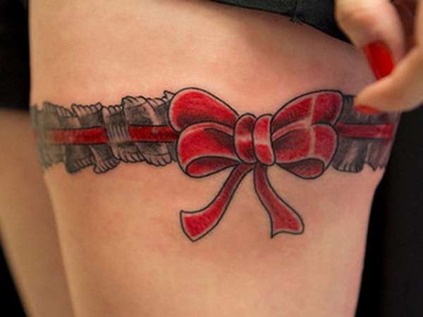 Tatuaje en el muslo - liguero con moño rojo