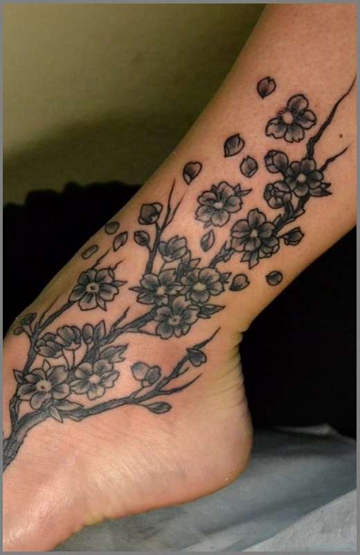 Tatuaje de flores de cerezo en blanco y negro en el tobillo