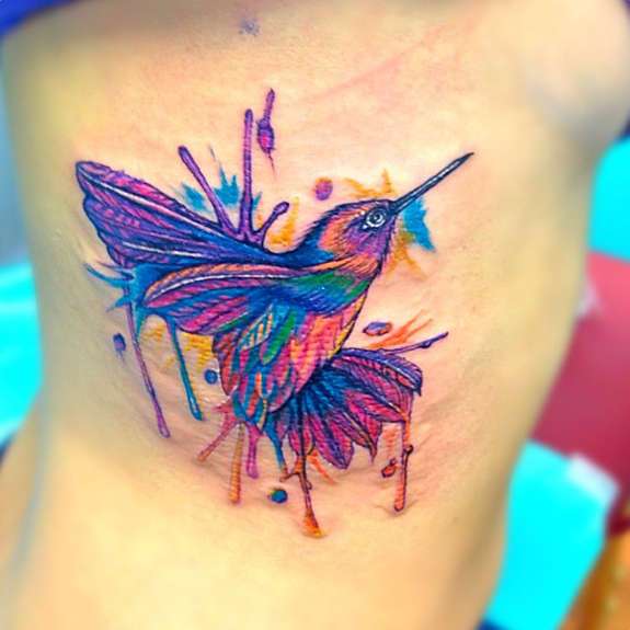 Tatuaje de colibrí en tonos violeta