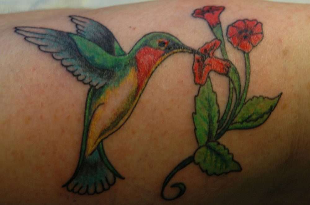 Tatuaje de colibrí y tres flores