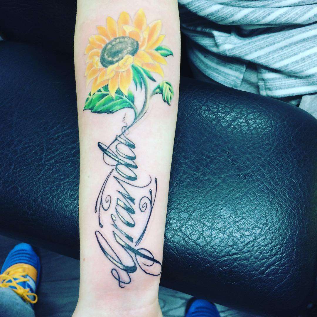 Tatuaje de girasol y palabra