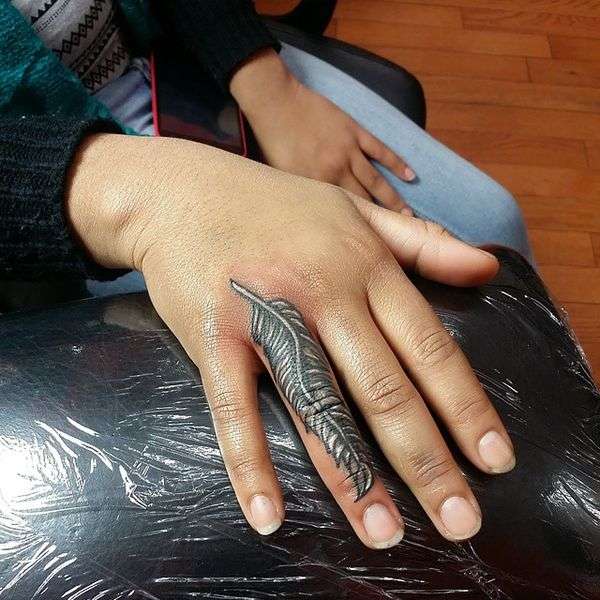 Tatuaje de pluma en el dedo