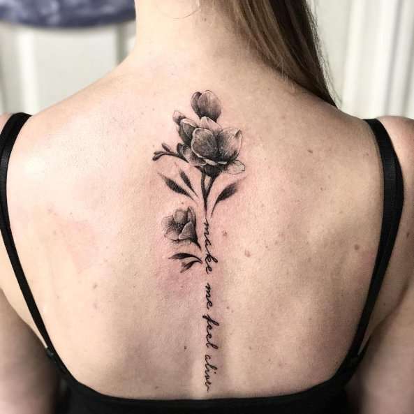 Tatuaje en la columna vertebral: flores y frase