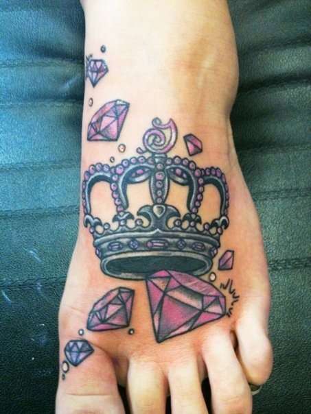 Tatuaje de corona con diamantes rosados en el pie