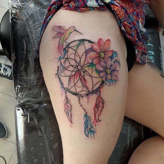 Tatuaje de atrapasueños, flores y colibrí en el muslo