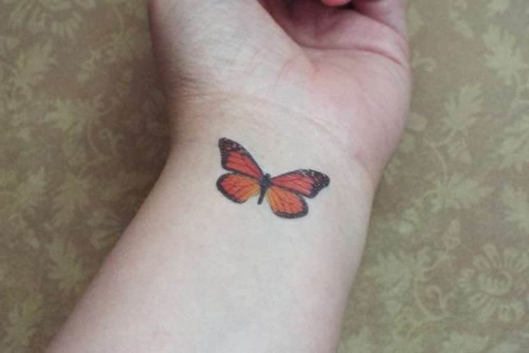 Tatuaje de mariposa monarca en la muñeca