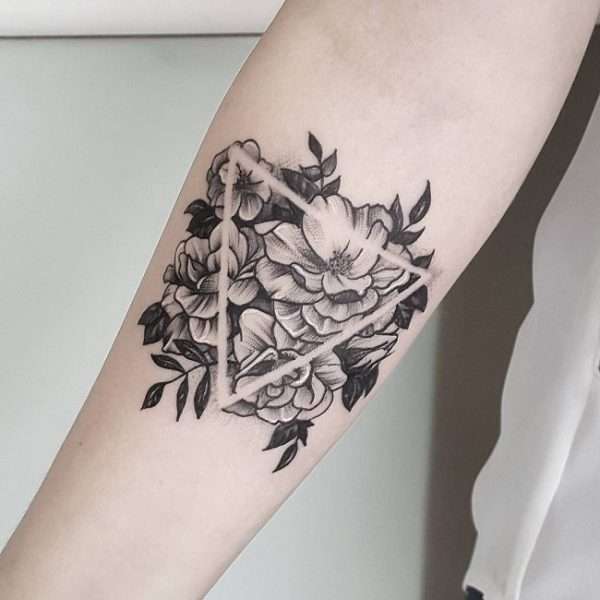 Tatuaje de triángulo en negativo con fondo de flores