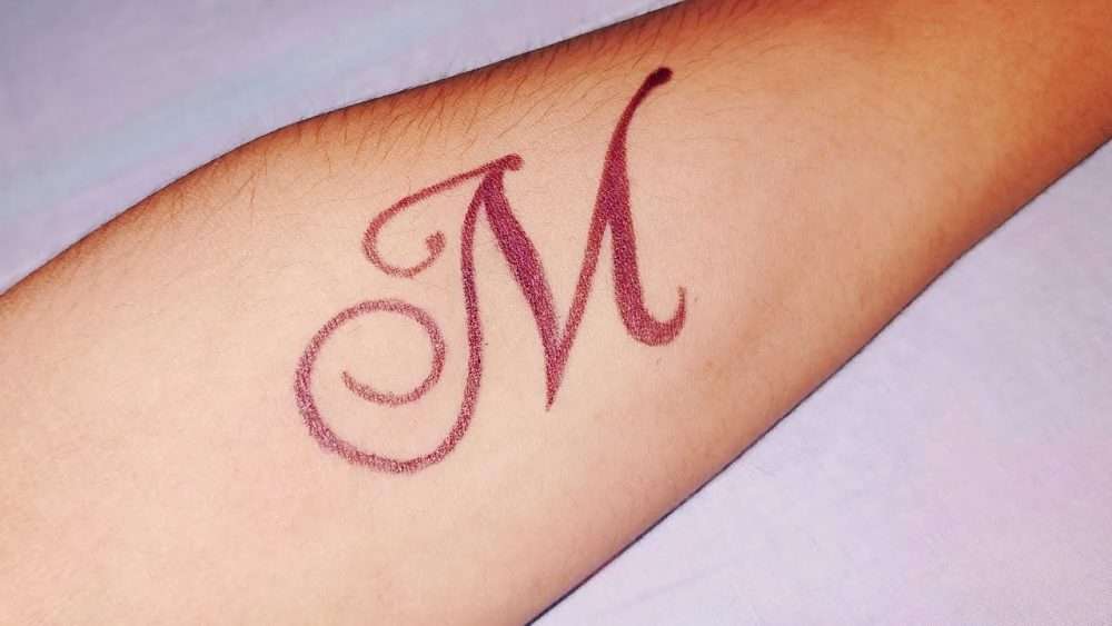 Tatuaje de letra "M" en color rojo