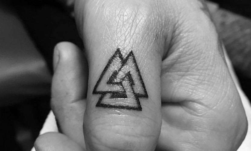 Tatuaje de triángulos pequeños en el dedo