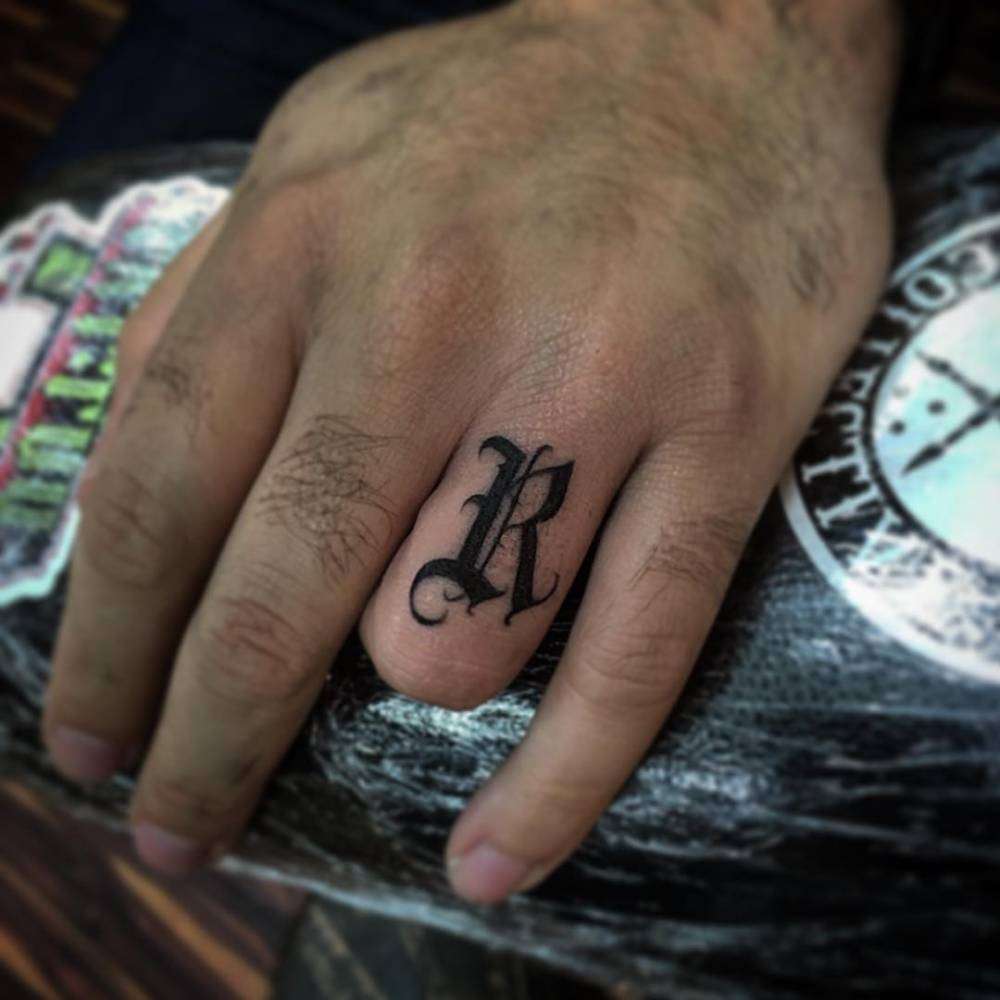 Tatuaje de letra "R" en el dedo